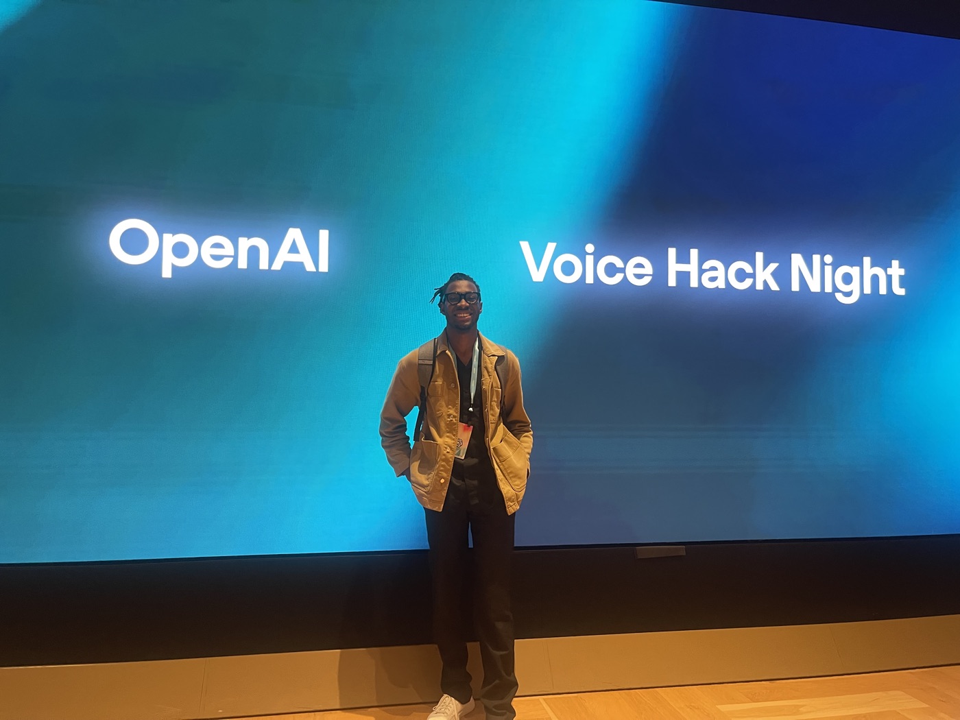 Manuel in front of a giant screen reading OpenAI Voice Hack Night